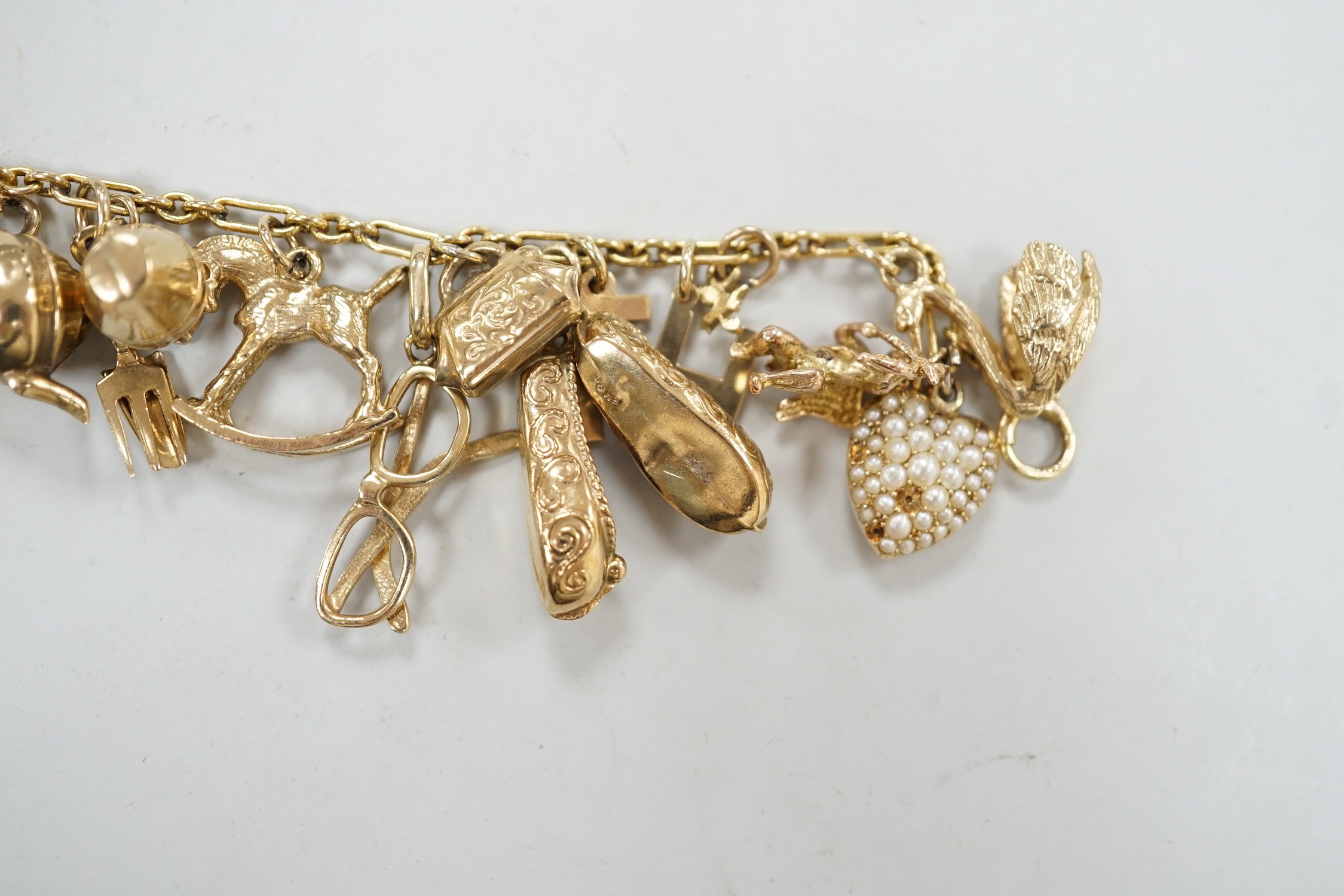 A 9ct charm bracelet, hung with assorted mainly 9ct gold charms, gross weight 46.1 grams.